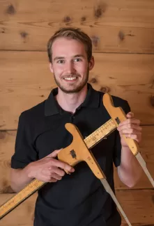 Jan Bucher mit einem alten Werkzeug in der Hand und ein schwarzer Schreinerei Eichenberger Polo Shirt
