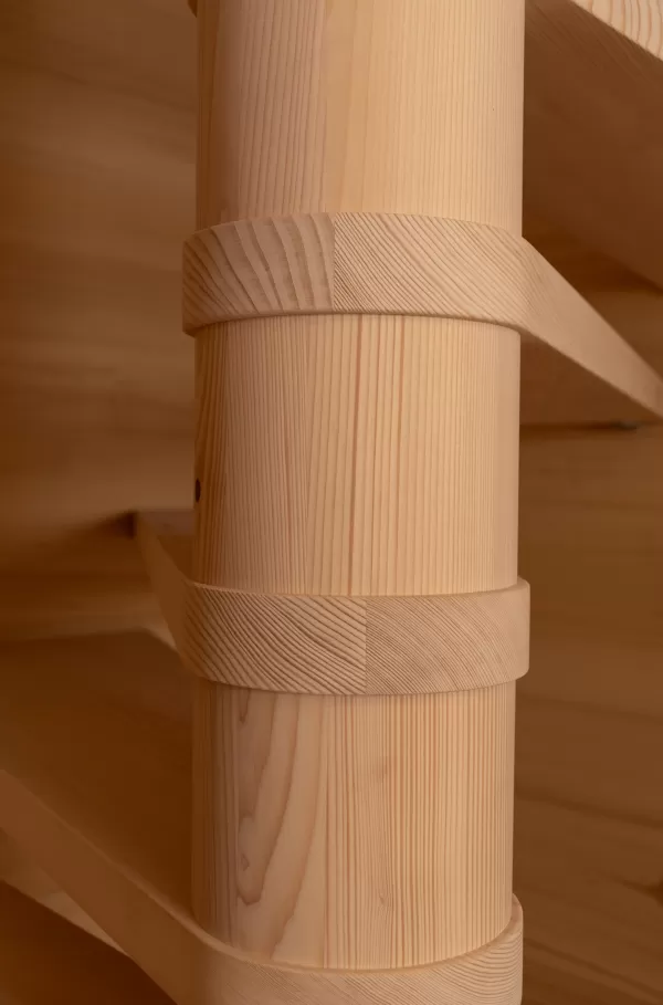 Detailaufnahme einer hellen Holz-Spindeltreppe mit geschwungenen Stufen in einem holzverkleideten Innenraum