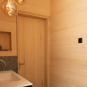 Heller Innenraum mit durchgehendem Holzausbau, Einbauschrank, Sitznische am Fenster und modernem grünen Kaminofen.